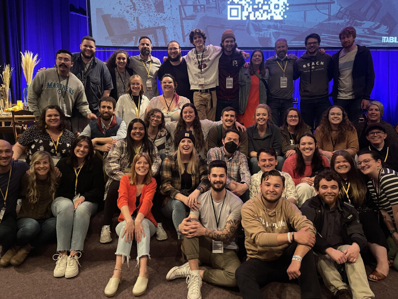 A crowd in front of a stage with a projected screen