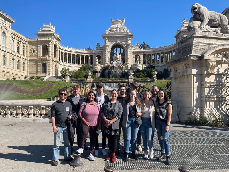 A group of people in front of a large courtyard with intricate statues and structures